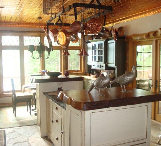 Rustic kitchen island shows distressed edges under live edge wooden tops and honed granite countertops